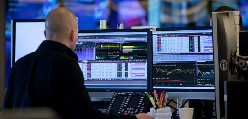 Man sitting at monitors with graphs