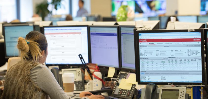 Woman sitting at desk of computer monitors